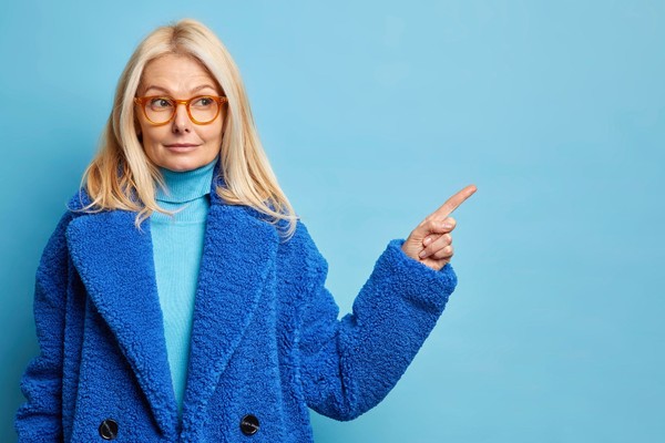 serious-blonde-forty-years-old-caucasian-woman-has-curious-expression-indicates-away-blank-space-wears-optical-glasses-stylish-fur-coat