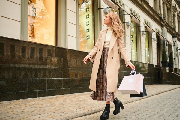attractive-stylish-blond-girl-beige-coat-with-shopping-bags-dreamily-looking-store-window-walking-city-street