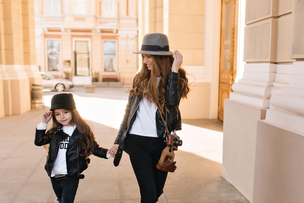 smiling-attractive-girl-felt-hat-with-retro-camera-walking-down-street-holding-little-sister-s-hand-magnificent-young-mother-leather-jacket-with-daughter-searching-nice-place-photoshoot