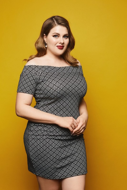 young-plump-woman-short-grey-dress-poses-yellow-surface-isolated-min